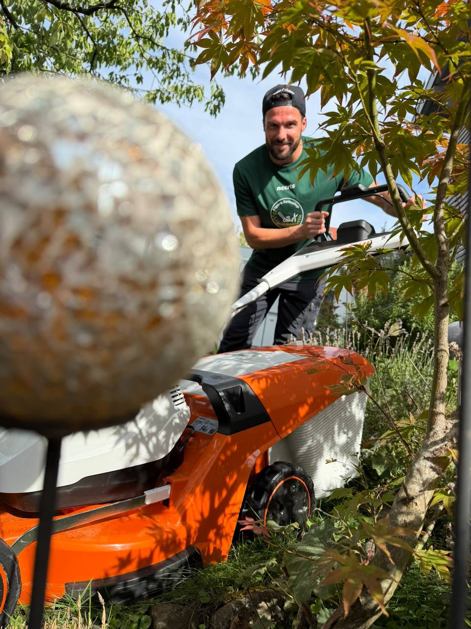 Jochen mäht zwischen Gartenkugel und Ahorn